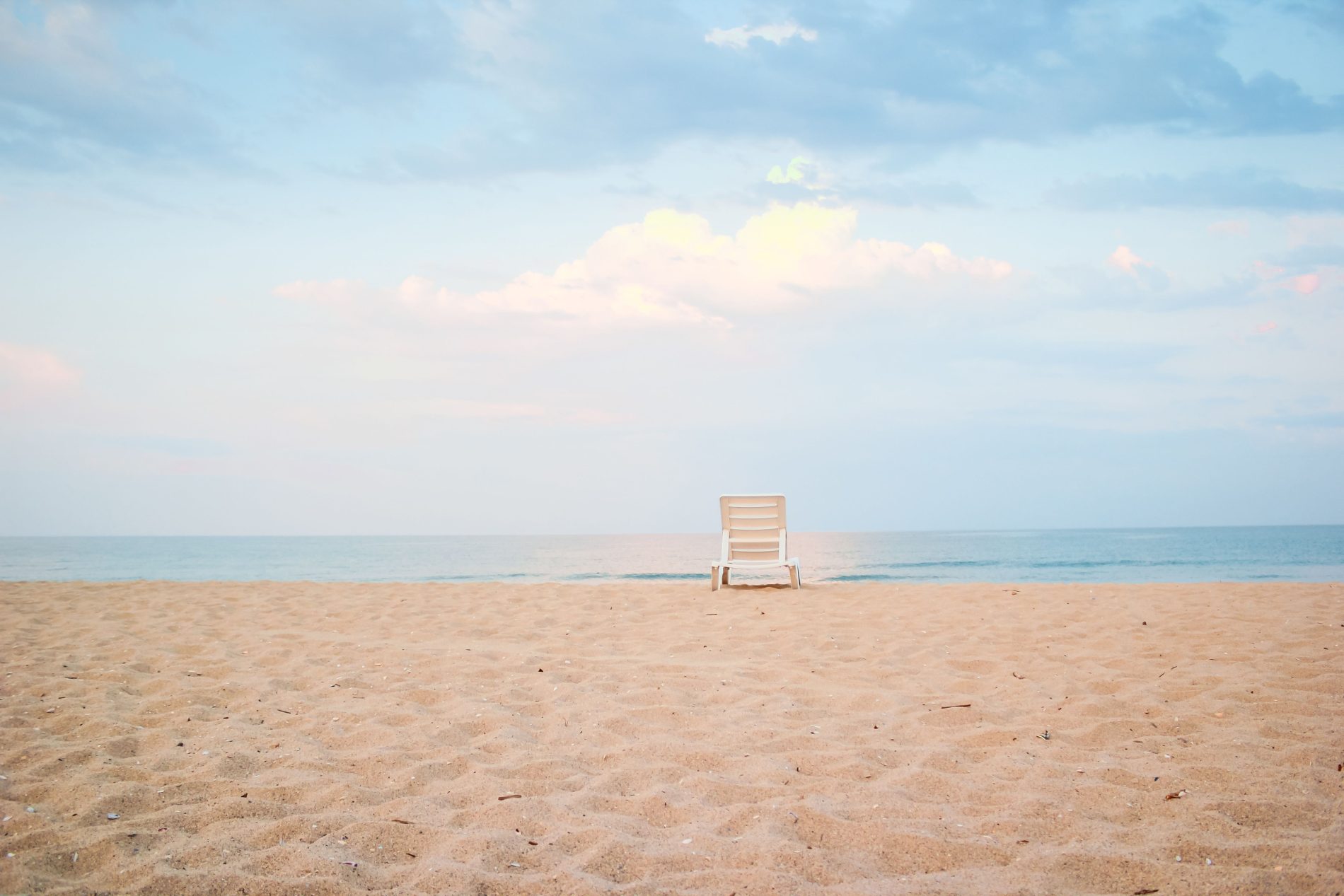 Empty sandy beach with lonely plastic sunbed located near calm sea at daytime